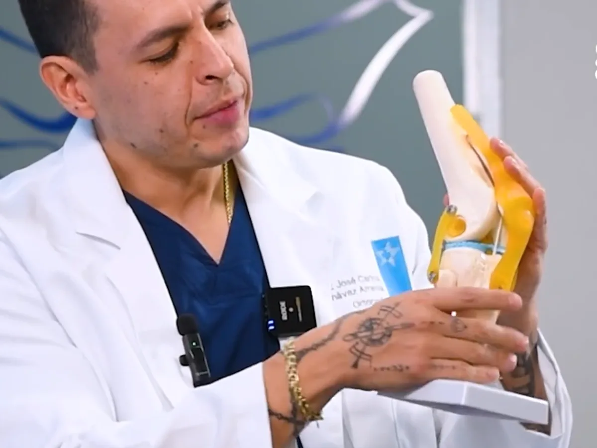 El Dr. José Carlos Chávez Arreola, con bata, explica una articulación con un modelo anatómico de rodilla